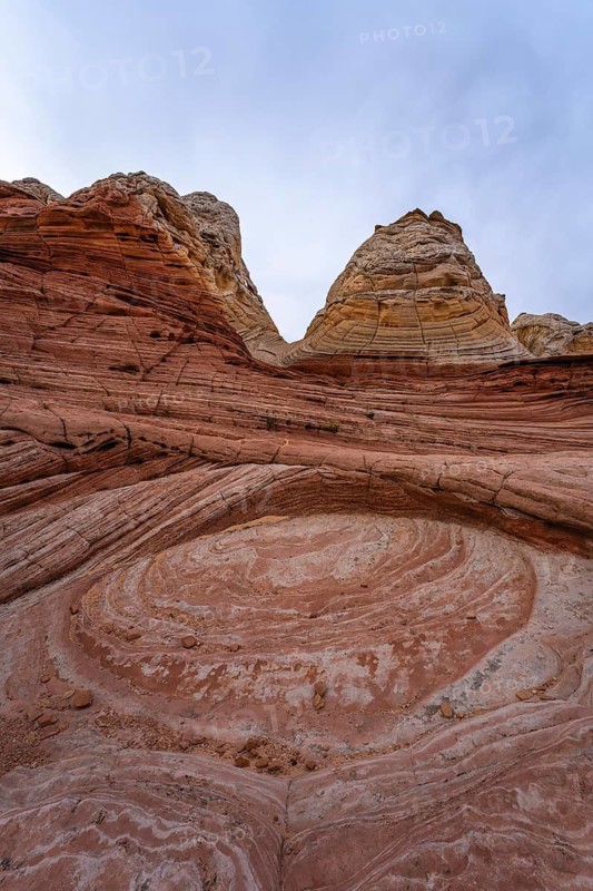 Striking image showcasing the intricate and colorful sandstone formations at White Pocket in Arizona, USA. The swirling patterns and layered rocks highlight the geological beauty of this remote area