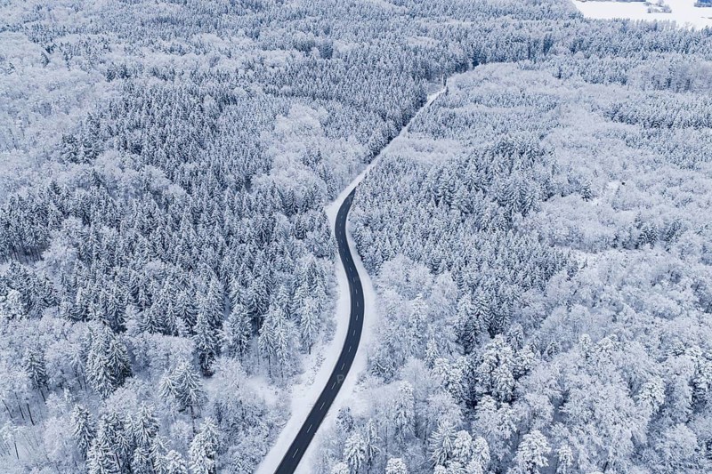 Winding road through snowy winter forest from the air, Gechingen, Calw district, Germany