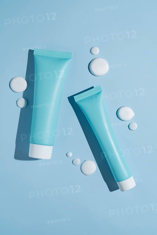 A vibrant image showcasing a cosmetics package with creamy smears on a soothing blue background. The composition highlights elegance and freshness, perfect for beauty product presentations