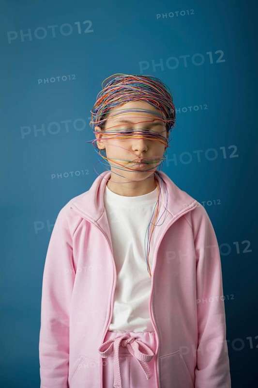 A child in a pink outfit is wrapped in colorful wires, symbolizing the entangling effects of the internet. The blue background highlights the theme of technology's influence on youth