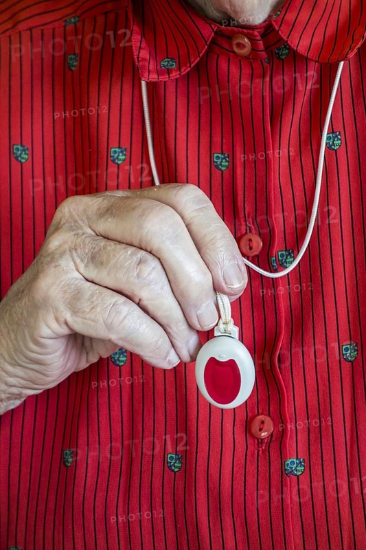 Close up of hand holding life-saving personal alarm for the elderly and disabled people showing pendant with push button