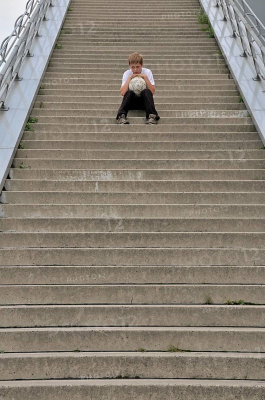 Lonely ten-year-old boy with his football, stairs to the viewing platform of the Chocolate Museum, Cologne, North Rhine-Westphalia, Germany