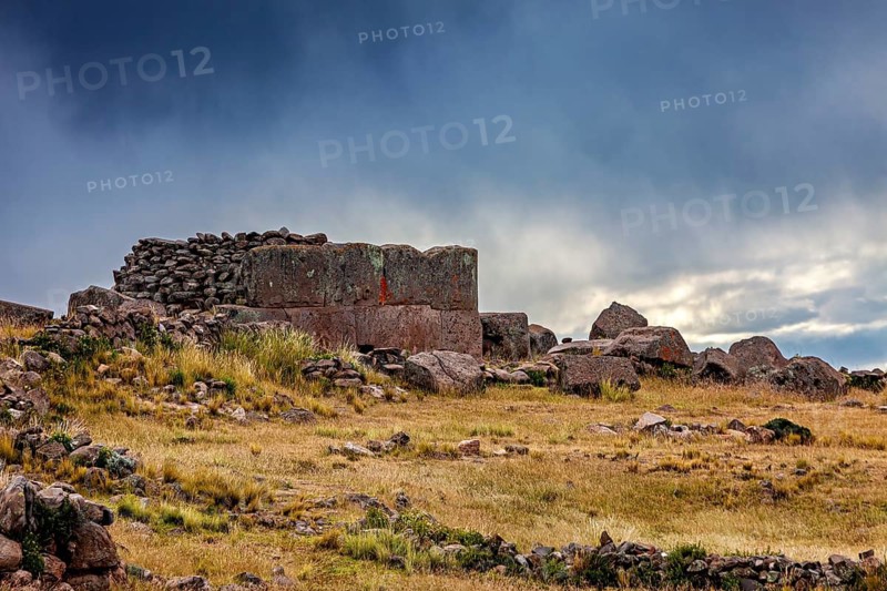 Stone construction on a hill under a dramatic dark sky, The Chullpas of Sillustani near Puno in Peru