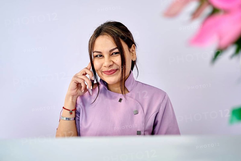 A staff member at a beauty salon engages with a client via phone, showcasing excellent customer service. The atmosphere is welcoming and professional, with floral accents