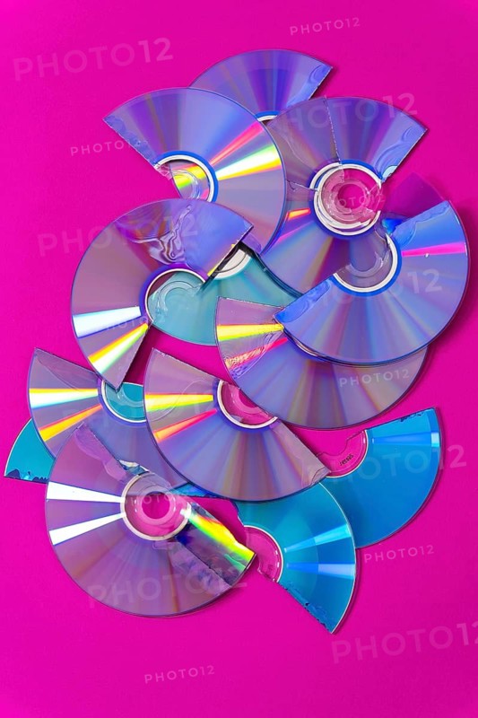 Top view of cut CDs and DVDs against a magenta background