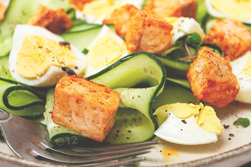 Delicious salmon and egg salad served on a plate with fresh cucumber and herbs for a healthy meal at lunchtime