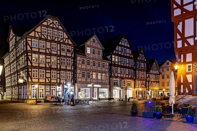 Illuminated half-timbered houses in a cobbled street at night, The old town centre of Melsungen