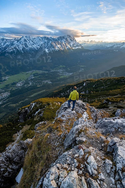 View of Wetterstein mountains with Zugspitze, mountaineer at the summit of Kramerspitz, at sunset, in autumn, Ammergau Alps, in autumn, Bavarian Alps, Bavaria, Germany