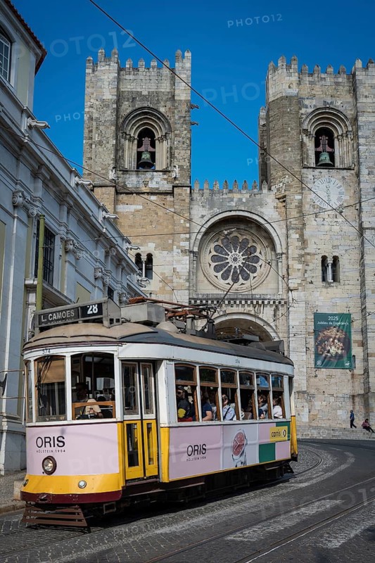 LISBON, PORTUGAL - MAY 19, 2025: Famous tram number 28 at the street and cathedral Se in the background