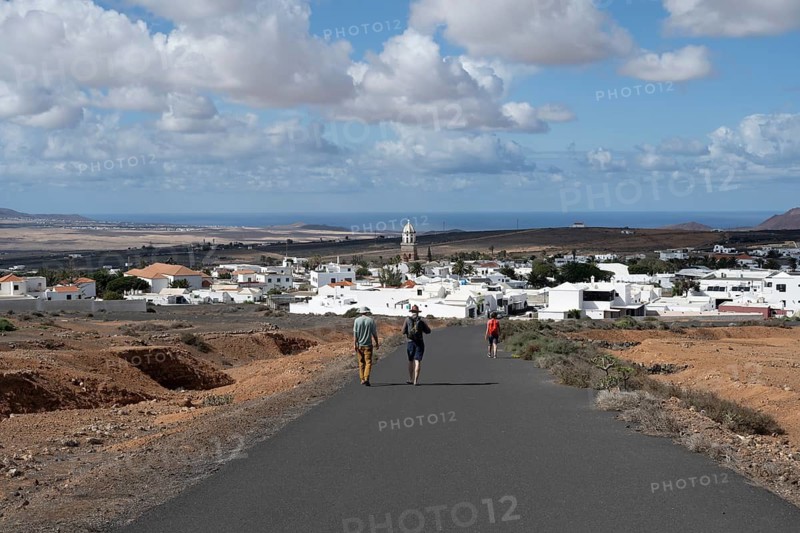 Tourists on a street near Teguise, view of town, white houses of Teguise with church tower, Lanzarote, Canary Islands, Spain