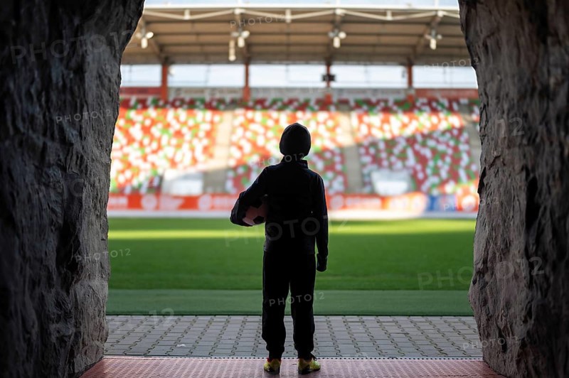 Young the boy with the ball standing in the players' tunnel and looking at the stadium