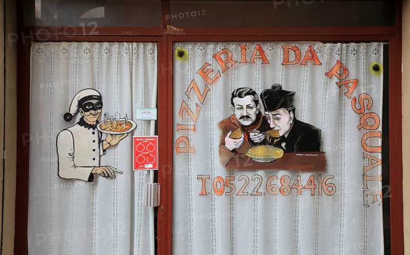 Italy, village of Brescello, advertisement for Pizzeria Pasquale, with a picture of Don Camillo and Peppone