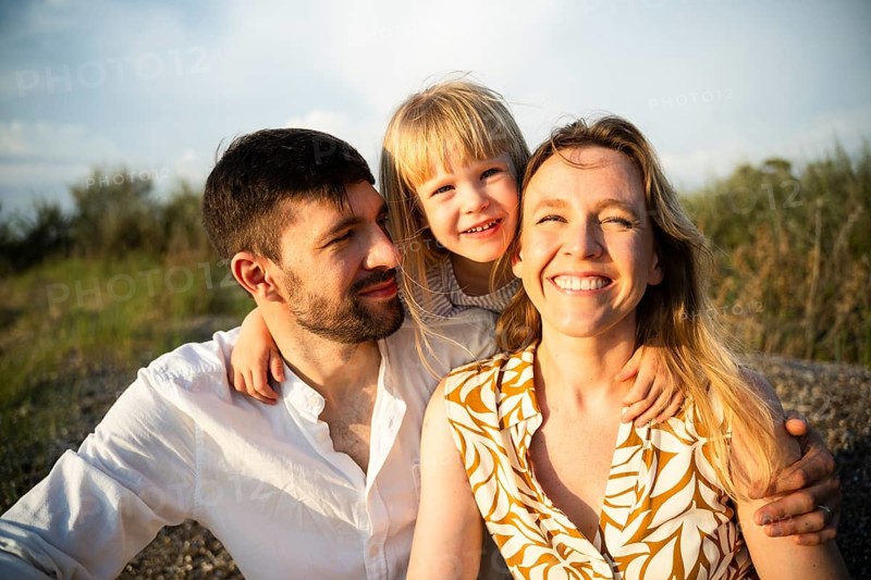 A joyful family of three enjoys a sunny day at a beach in Italy. The scene captures the happiness and togetherness of a memorable family vacation by the sea