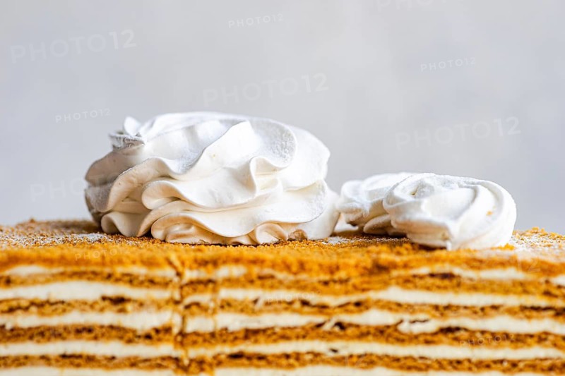Indulge in this exquisite homemade honey cake, layered with creamy sour cream sauce and elegantly topped with delicate vanilla zephyr marshmallows for a delightful treat