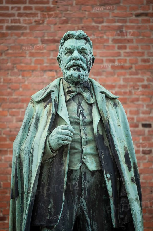 Bronze statue of Carl Jacobsen, Danish brewery entrepreneur, art collector and benefactor, in front of brick wall, Carlsberg district, Copenhagen, Denmark