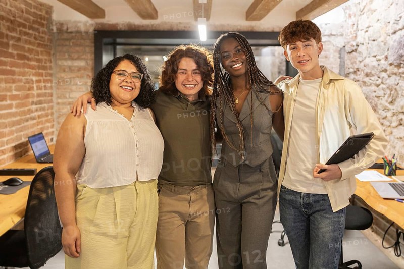 A diverse group of young professionals in a coworking space, embracing teamwork and collaboration with technology, showcasing an inclusive work environment