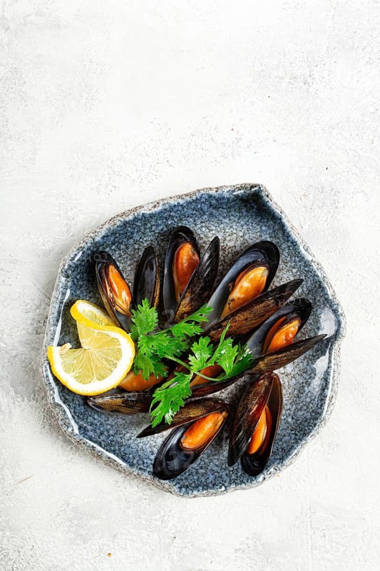 Mussels in shells, boiled in their own juice, in a bowl, gray background, top view, homemade, no people