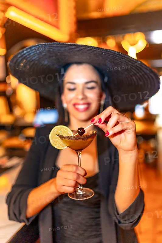 Close-up vertical portrait of a chic woman drinking martini cocktail in a luxury bar