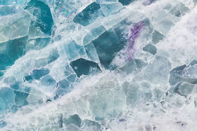 Detailed macro image of a fluorite, calcium fluoride, slab from China, featuring translucent layers of teal, white, and purple hues, with intricate crystal structures and natural formations