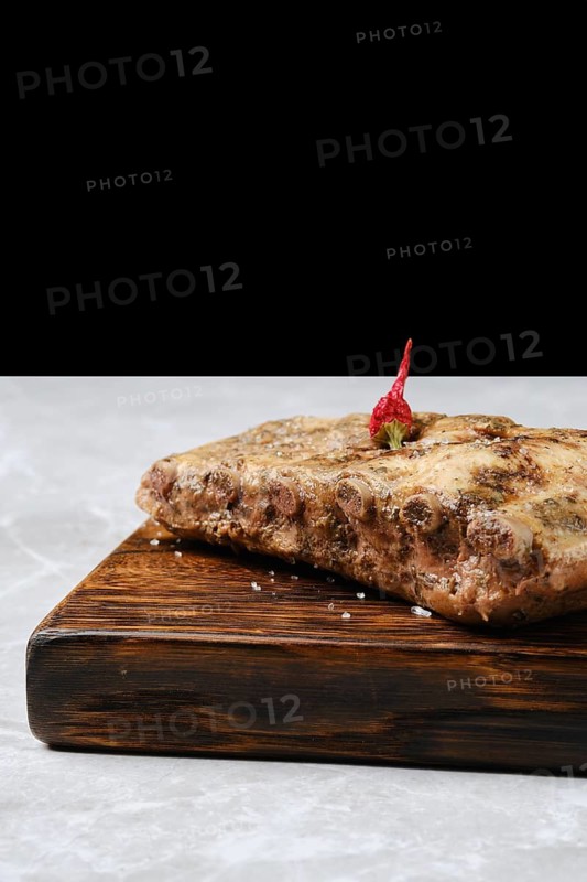 Close-up view of baked spicy pork ribs on a rustic wooden board