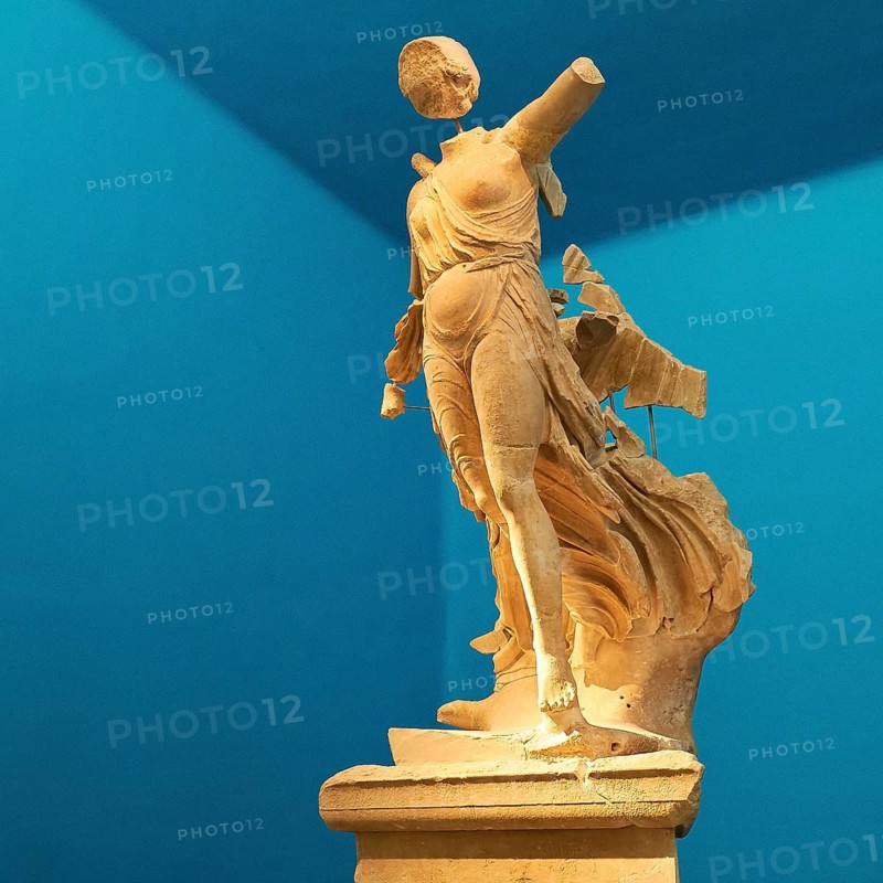 The Nike of Paionios, statue of the goddess of victory Nike from Parisian marble, fragment of an ancient female marble statue in dynamic pose against a blue background, Olympia Archaeological Museum, Ancient Olympia, Olympia, Peloponnese, Greece