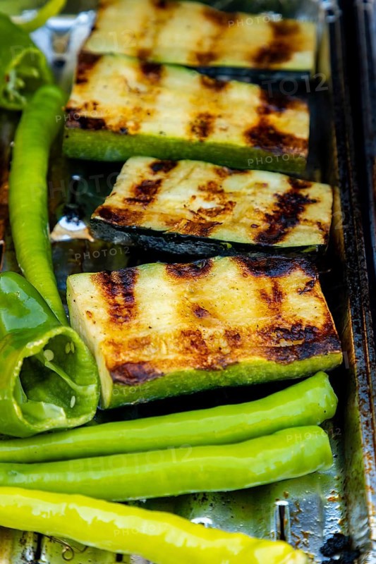 Grilled courgettes and green peppers with grill strips on a barbecue