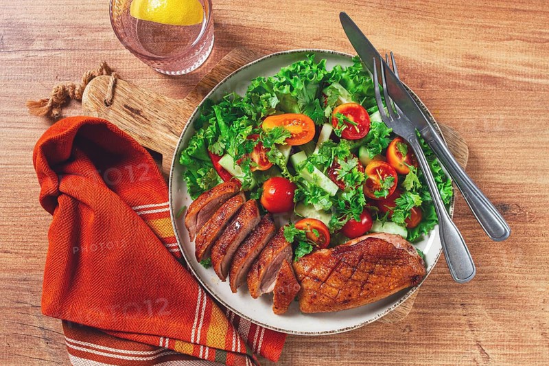 Delicious grilled duck breast served with fresh garden salad and cherry tomatoes at a rustic dining table