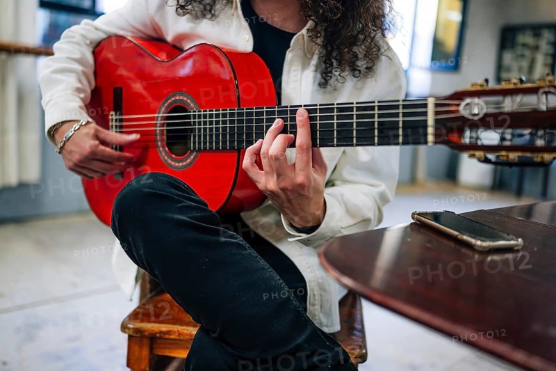 Anonymous Latin man playing red bass guitar in studio