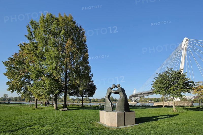 Garden of two banks with sculpture Encounter by Josef Fromm 1994 and Passerelle des Deux Rives cable-stayed bridge across the Rhine, modern art, two bronze sculptures, hug, encounter, park, banks of the Rhine, Kehl, Ortenau, Baden-Württemberg, Germany