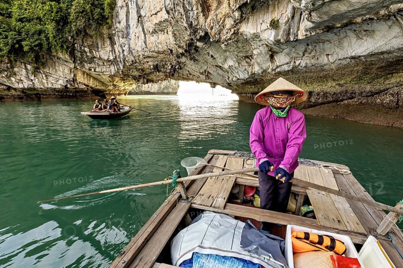 Guided boat under a huge rock cave, rowing boats for tourists in Halong Bay in Vietnam