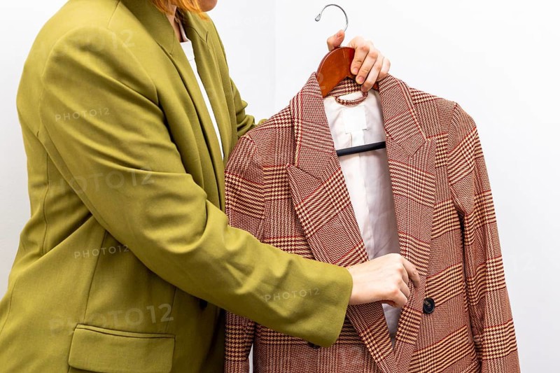 An image consultant assists a client in selecting a stylish jacket, emphasizing personalized fashion choices. The scene highlights attention to detail and modern style