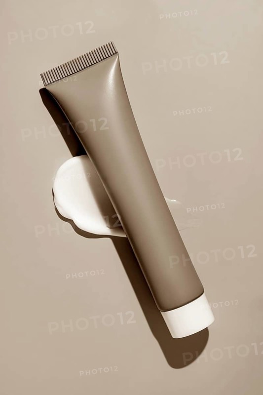 A sleek cosmetics package with creamy smears elegantly displayed on a serene background, showcasing modern beauty products with a touch of artistic elegance and luxury