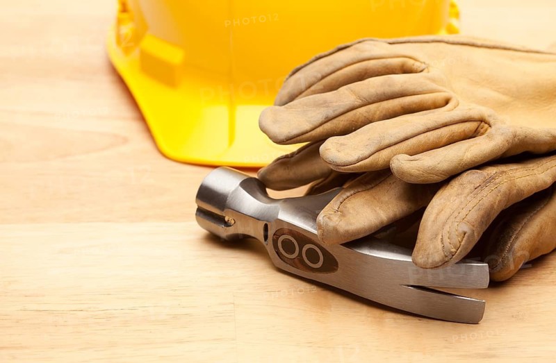 Yellow Hard Hat, Gloves and Hammer on Wood Surface