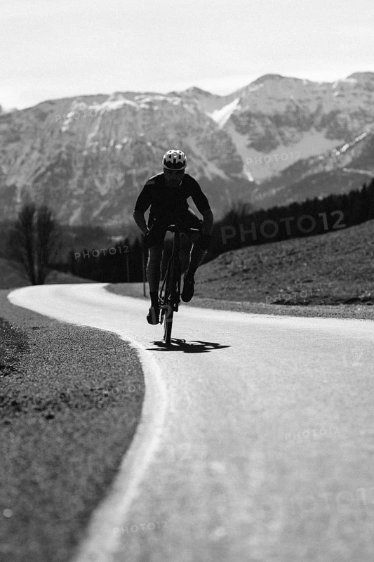 Road bike rider in spring in the Allgäu against the picturesque backdrop of the Alps, Bavaria, Germany