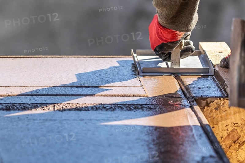 Construction Worker Using Hand Groover On Wet Cement Forming Coping Around New Pool