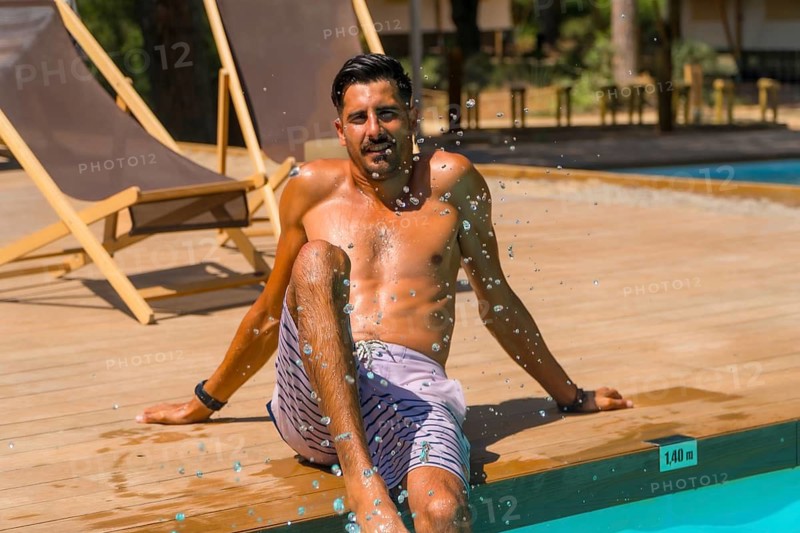 Tourist enjoying a sunny summer day by the poolside, splashing water with his feet and creating refreshing droplets, reveling in the joy and relaxation of vacation leisure