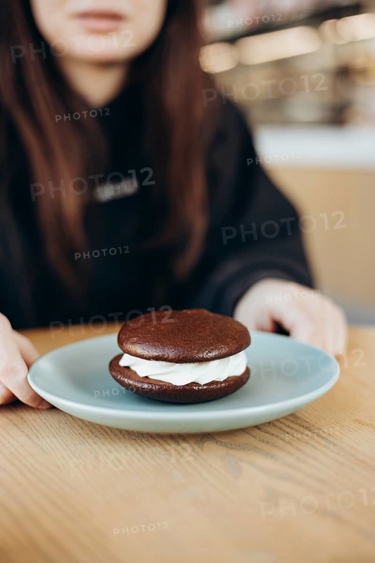 A tantalizing chocolate whoopie pie with creamy filling rests on a light blue plate, tempting taste buds with its rich and indulgent appearance, ready to be savored