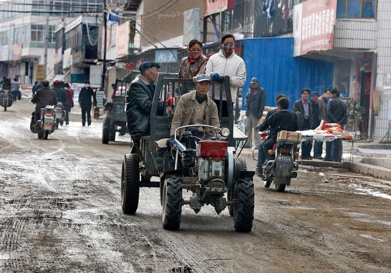 Xining, CHN, 27.02.09 - Villagers are picked up on the back of a tractor trailer. Street scene in a village near Xining, CHINA