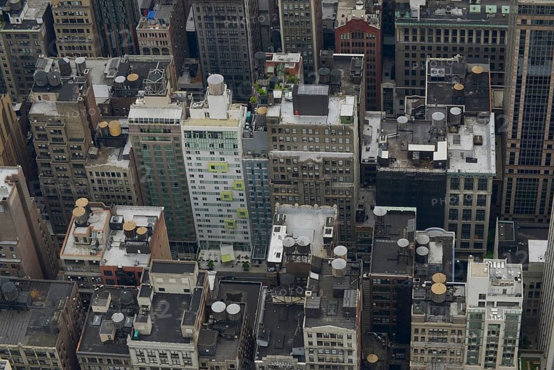 Bird's-eye view of a densely packed section of Manhattan showcasing varying building architectures and clustered rooftops