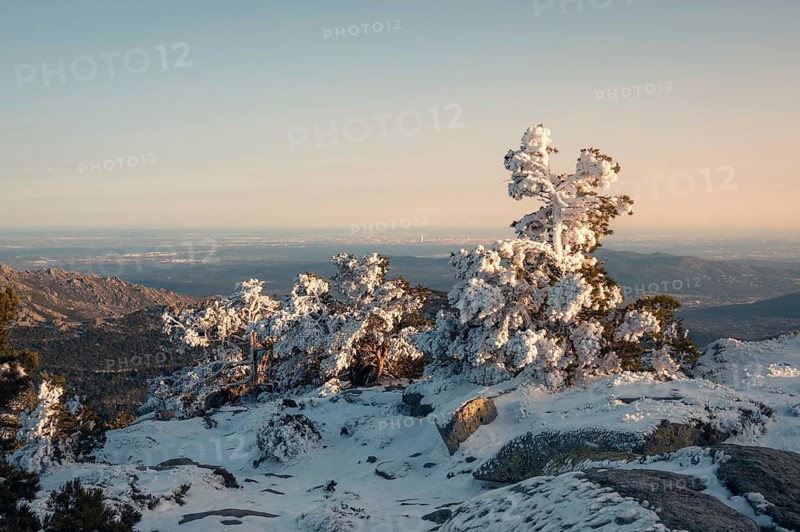 A breathtaking view of Siete Picos in Guadarrama Mountains, Madrid, covered in snow. The sun casts a warm glow on the frosty landscape, showcasing the natural beauty