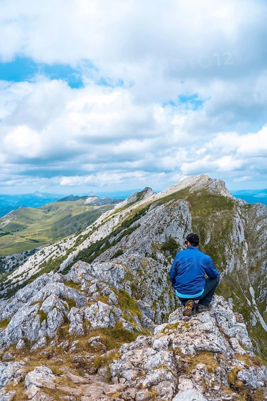 Mount Aizkorri 1523 meters, the highest in Guipúzcoa. Basque Country. Ascent through San Adrián and return through the Oltza fields. A young man in blue sitting high on top