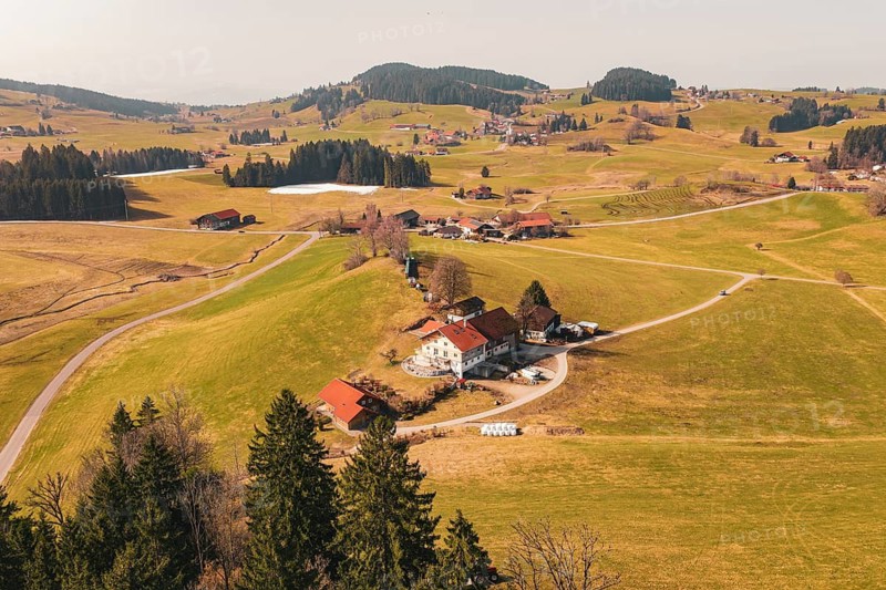 A quiet alpine landscape with scattered houses on rolling hills and clear views, Oberreute, Allgäu, Germany