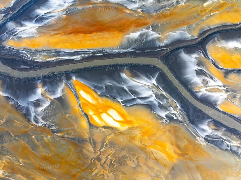 From above, this image captures intricate abstract nature textures. The flowing patterns and vibrant earth tones are shot from an aerial view, highlighting the unique landscape