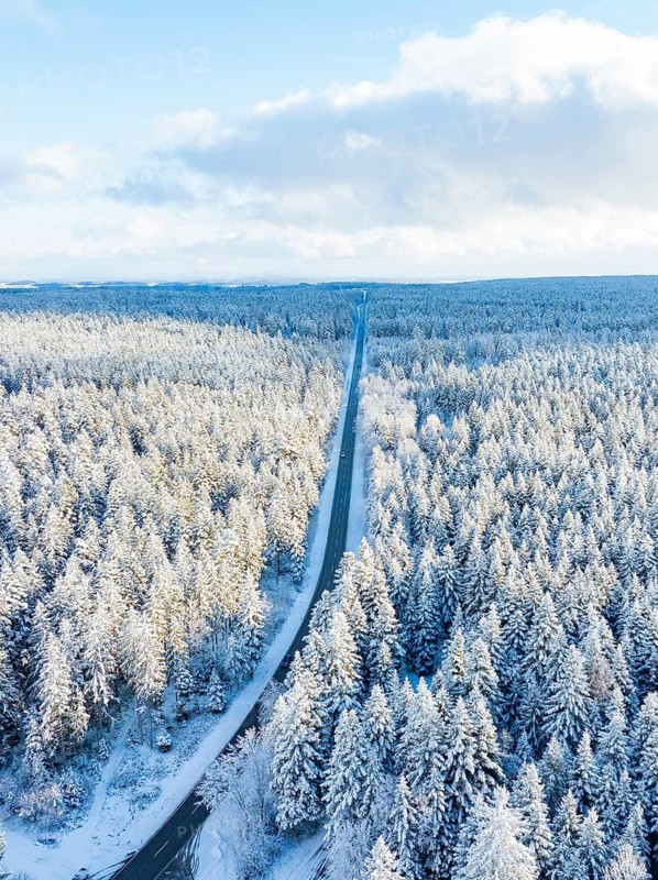 A long, straight road stretches through a snow-covered forest, aerial view, Bad Wildbad, district of Calw, Black Forest, Germany