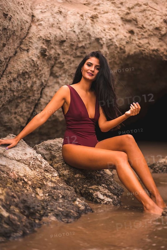 Lifestyle of a brunette Caucasian woman with a maroon swimsuit sitting enjoying, summer on the beach of Cabo de Gata, Nijar. Andalucia, Spain