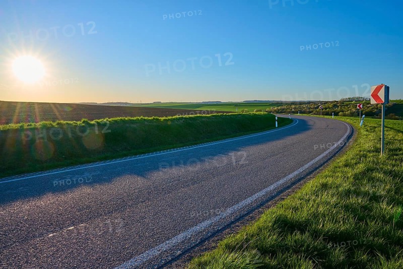 Street at sunset, which runs through soft, green landscape, bright sky and peaceful atmosphere, Bütthard, Lower Franconia, Bavaria, Germany