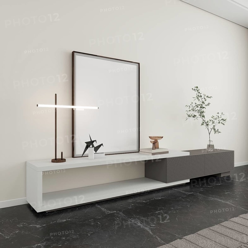 A minimalist interior scene featuring a sleek console table against a neutral wall. It holds a modern lamp, decorative items, and a plant, creating an elegant ambiance