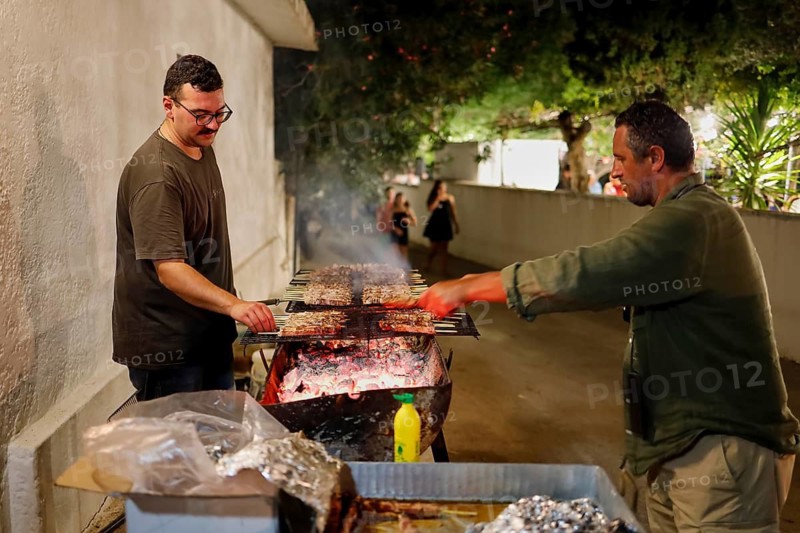 Two men grilling meat at a night street party, festival, Panagia Kamariani, Megalo Chorio, Zero Waste Island, Tilos, Dodecanese, Greek Islands, Greece