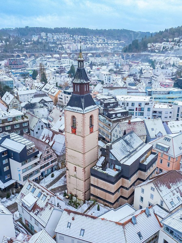 Old tower, Urban panorama with church tower and snow-covered roofs in a hilly winter landscape, Nagold, Black Forest, Germany