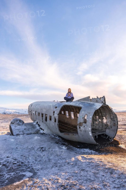 Woman sitting on the plane of Solheimasandur concentrated in meditation in Iceland